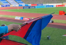 Ein Kind hält eine blau-rote Fahne, im Hintergrund das Stadion.