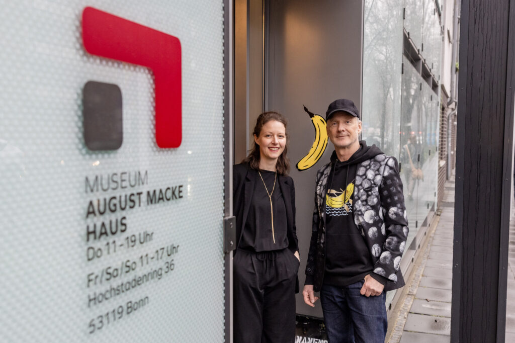 Direktorin Dr. Frederike VOßKAMP (August Macke Haus) und Streetart Künstler Thomas BAUMGÄRTEL (Bananensprayer)stehenam Eingang des August Macke Haus vor der EXCELLENZBANANE