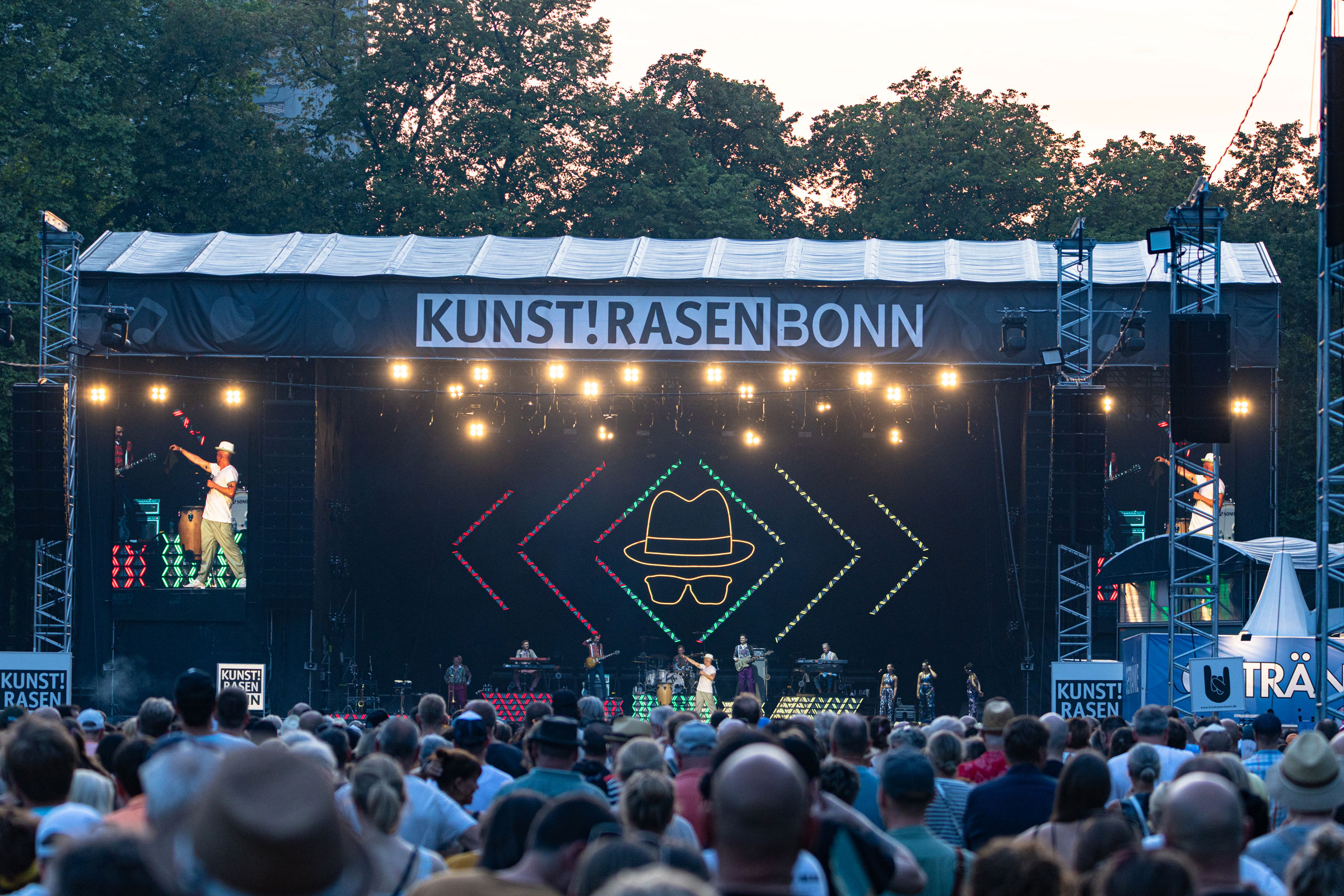 Eine Bühne, über der "Kunst!Rasen Bonn" steht. Davor sehr viele Menschen.