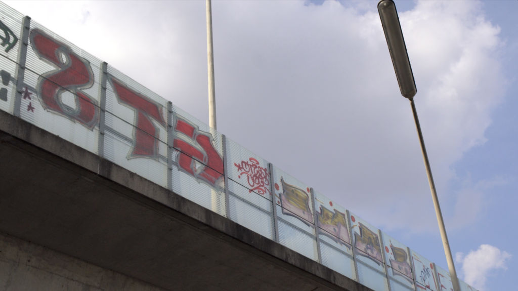 Ein Farbfoto der Vorlandbrücke der Bonner Nordbrücke respektive Friedrich-Ebert-Brücke. Man sieht die Bettonbrücke und darauf eine durchsichtige Absperrung bzw. Lärmschutzwand, welche mit Grafitti beschmiert ist.